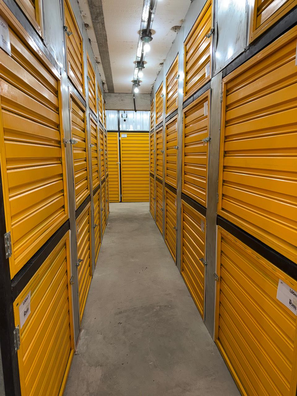 Corredor de boxes individuais do Mr. Boxes, com portas amarelas de enrolar dos dois lados